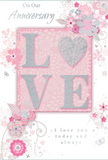 This anniversary card is captured as a delicate tribute to enduring romance, its design layered in soft pastel pinks and silvery greys that evoke the tranquillity of a quiet walk through Epsom's tree-lined streets. The focal point is the word LOVE, spelled out in raised, softly glittered letters that invite the fingertips to explore. The O is imaginatively replaced by a shimmering silver heart, slightly embossed and textured with fine glitter, making it appear like a cherished charm resting within the word. Around this centrepiece, a gentle cascade of blossoms in blush and mauve spreads outward, painted with an almost watercolour softness. Petals blur at the edges, and subtle shading adds depth, suggesting roses and small garden flowers much like those found in carefully composed anniversary bouquets. Slender stems and vines wind through the design, their fine lines curving gracefully to create a sense of movement. Tiny flourishes-scattered petals, delicate swirls, and discreet butterfly shapes-add a light touch of whimsy while maintaining the card's overall sense of calm. The background shifts from a soft pink centre to a paler outer edge, allowing the floral artwork and raised lettering to stand forward. Above and below the main motif, the words On Our Anniversary and I love you today and always are written in an understated, flowing script that feels sincere rather than ornate. The entire composition carries a sense of intimate celebration, like a quiet evening at home in Epsom with a beautiful bouquet on the table-soft-spoken yet profoundly heartfelt, perfect for marking another year of shared life and love.